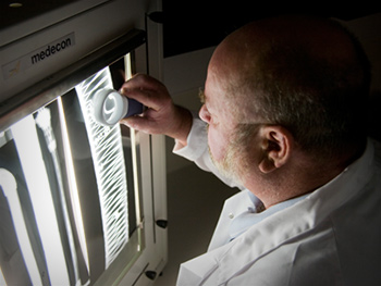 A scientist examines an x-ray image of materials affected by structural fatigue.