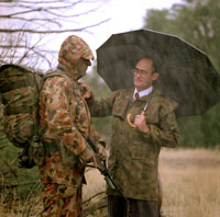 A photo of Graeme Eggleston assessing raingear on a soldier in the rain